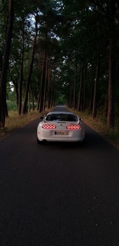 a white sports car parked on the side of a road in front of some trees