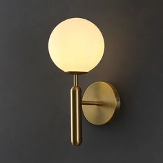 a wall light that is on the side of a wall with a white glass ball