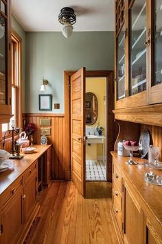 a kitchen with wood floors and cabinets in the center, along with an open door that leads to another room