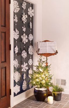 a small christmas tree sitting in front of a window with an open book on it