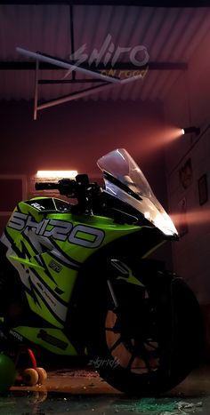 a green motorcycle parked in a garage next to a ball and some lights on the ceiling