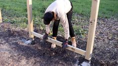 a man is digging in the ground with his work boots on and working to build a wooden structure