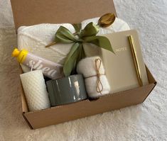 an open box with items inside sitting on a white carpet next to a cup and spoon