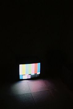 a television sitting on top of a tiled floor in the middle of a dark room