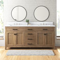 two round mirrors are above the double sink vanity in this modern bathroom with wood flooring and white brick walls