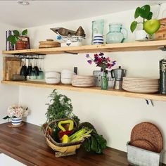 the shelves in the kitchen are filled with dishes and bowls, including fruit and vegetables