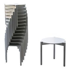 a stack of chairs next to a table with a white top and grey legs on each side