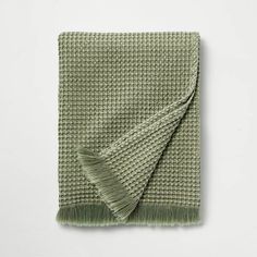 a green blanket folded on top of a white wall