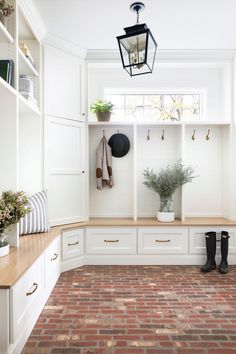 a brick floored entryway with white cabinets and shelves filled with potted plants