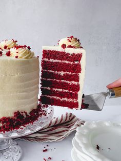 a red velvet cake with white frosting and sprinkles is being cut