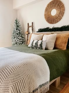 a bedroom decorated for christmas with green bedding and white pillows, pine tree in the corner