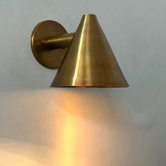 a wall mounted light with a cone shaped shade on it's face and arm