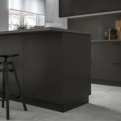 a kitchen with an island and stools in front of the counter top, next to a potted plant