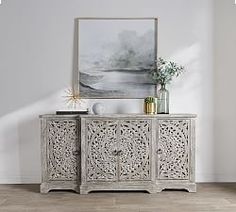 an ornate sideboard with two vases on top and a painting hanging above it