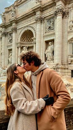 a man and woman kissing in front of a building