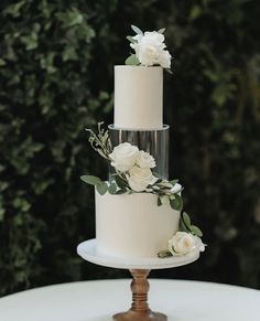 a three tiered cake with white flowers and greenery