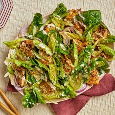 a salad with chicken and lettuce on a plate next to chopsticks