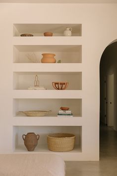 a white shelf filled with vases and bowls