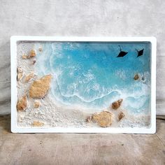 an aerial view of the ocean with rocks and birds flying over it, taken from above