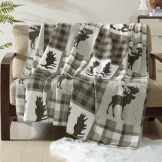 a plaid blanket with moose silhouettes on it sitting on a chair in front of a window