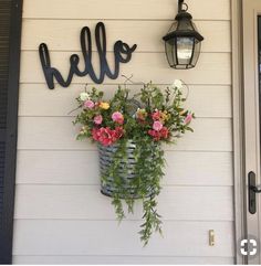 a basket with flowers hanging from the side of a house next to a light fixture