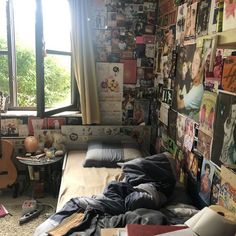 a bedroom with posters on the wall and an unmade bed in front of a window