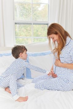 a woman in pajamas sitting next to a boy on a bed