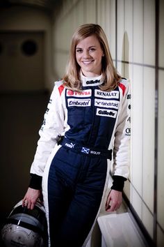 a woman in a racing suit holding a helmet