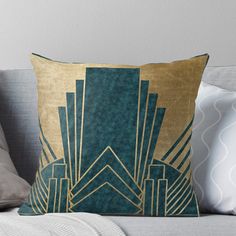 a blue and gold throw pillow sitting on top of a couch with pillows in front of it