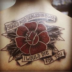 the back of a woman's shoulder with a rose and ribbon tattoo on it