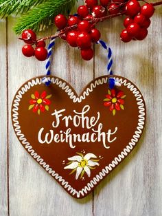 a wooden heart hanging on a wall with berries and holly branches in the foreground