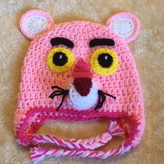 a crocheted pink hat with yellow eyes and a cat's face on it