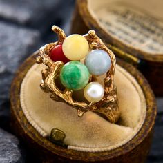 a ring with four different colored stones in it sitting on top of a wooden box