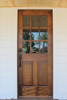 a wooden door with glass panes in front of a white house