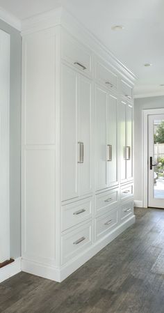 an empty kitchen with white cabinets and wood floors