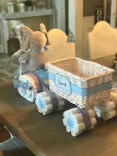 a baby elephant sitting on top of a wooden table next to a basket filled with diapers