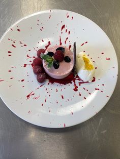 a white plate topped with fruit and whipped cream covered in red blood splatters