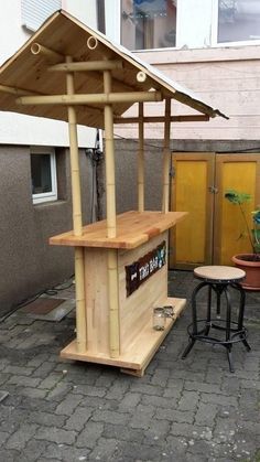 a small wooden stand sitting on top of a brick patio next to a potted plant