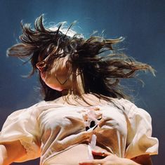 a woman with her hair blowing in the wind on stage at a music festival or concert