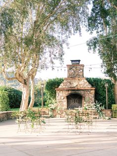 an outdoor fireplace surrounded by greenery and trees