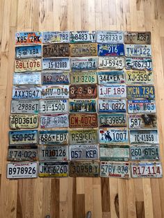 many different license plates are arranged on a wooden floor in a room with wood floors