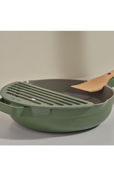 a green cast iron skillet with a wooden spatula in the bottom and lid