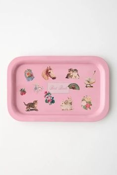 a pink tray with various stickers on the front and back of it, including cats