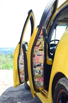 the back door of a yellow car with stickers all over it's sides