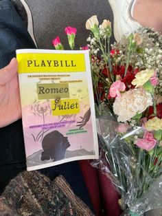 a person holding up a book with flowers in front of it and the title playbill