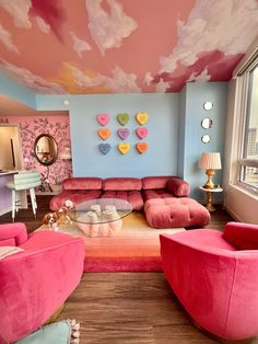 a living room filled with pink furniture and walls painted in pastel colors on the ceiling