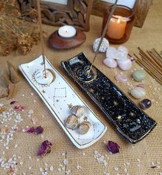 two candles and some other items on a table with flowers, rocks and stones around them