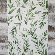 a painting of green leaves on a white wooden background with wood planks in the background