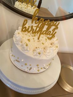 there is a white cake with gold decorations on it and the words happy birthday written on top