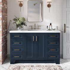 a bathroom vanity with blue cabinets and white counter tops, gold pulls on the doors